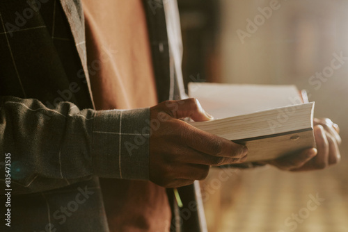 Closeup of hands of unrecognizable African American man standing indoors reading book photo