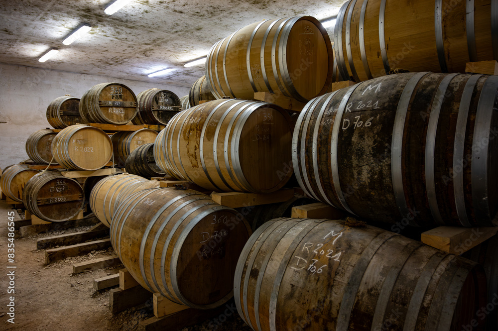 Aging process of cognac spirit in old dark French oak barrels in cellar in distillery house, Cognac white wine region, Charente, Segonzac, Grand Champagne, France Aging process of cognac spirit in old dark French oak barrels in cellar in distillery house, Cognac white wine region, Charente, Segonzac, Grand Champagne, France