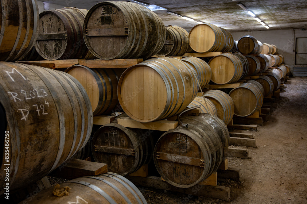 Aging process of cognac spirit in old dark French oak barrels in cellar in distillery house, Cognac white wine region, Charente, Segonzac, Grand Champagne, France Aging process of cognac spirit in old dark French oak barrels in cellar in distillery house, Cognac white wine region, Charente, Segonzac, Grand Champagne, France