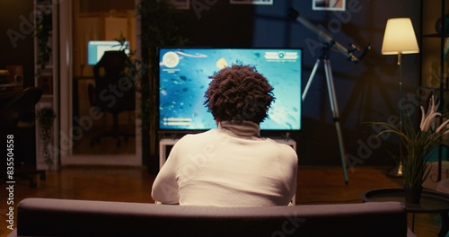 Canvastavla BIPOC gamer playing classic arcade space shooter videogame on modern smart TV, shooting asteroids