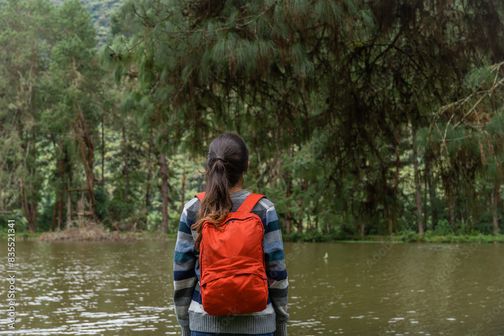 Woman meditating in front of a lake and a pine forest Woman meditating in front of a lake and a pine forest