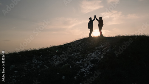 Teenage hiking adventure, a cheerful teen girl and a teen boy giving high five on the mountain top, enjoying success. Fun, inspiration, and recreation concepts.