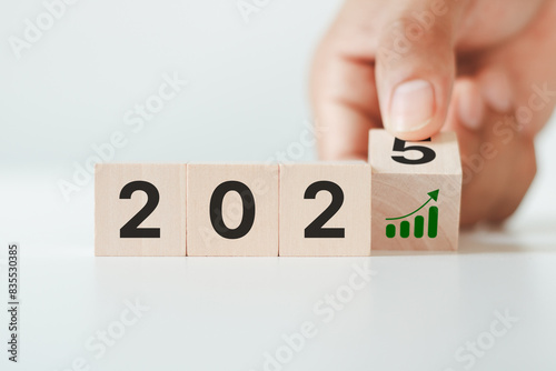 Flipping wooden cubes to 2025 and growth performance. 2025 business growth, acceleration concept. New year business goals, plan, strategy. Banner for the new action plan ,annual plan, growth, target. photo