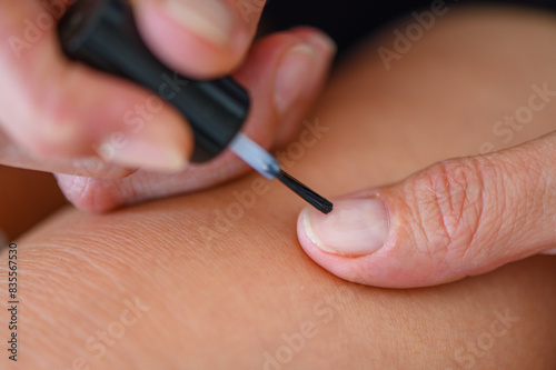 woman applying nail polish doing manicure