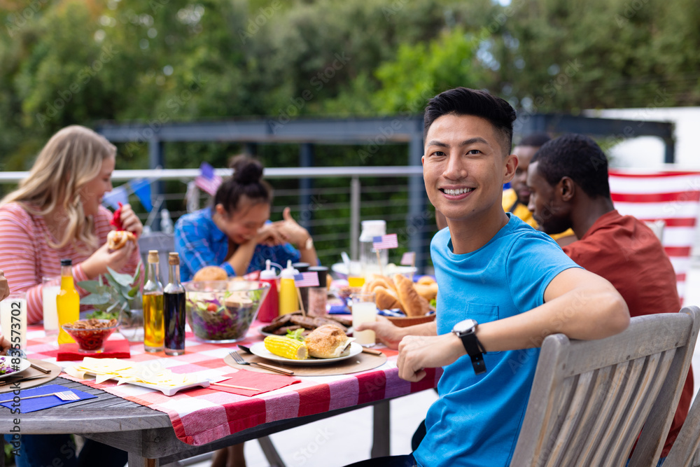 Portrait of happy diverse group of friends talking and having dinner at balcony with flags of usa Portrait of happy diverse group of friends talking and having dinner at balcony with flags of usa