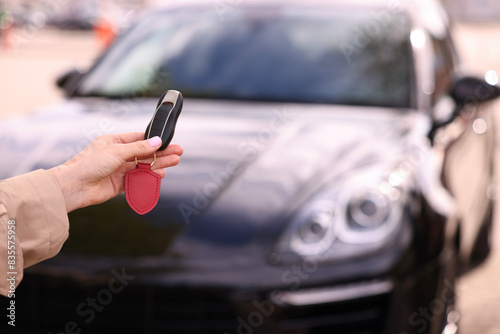 Woman holding car flip key near her vehicle outdoors, closeup © New Africa