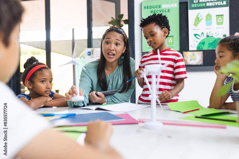 A middle-aged biracial teacher and four young students craft together in a classroom A middle-aged biracial teacher and four young students craft together in a classroom