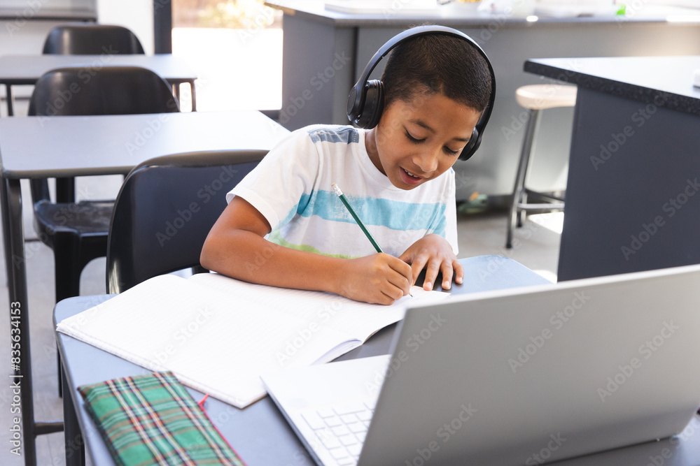 Biracial boy studies intently at school using a laptop Biracial boy studies intently at school using a laptop