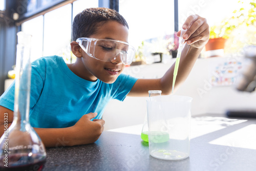 Biracial boy engaged in a science experiment at school in the classroom photo