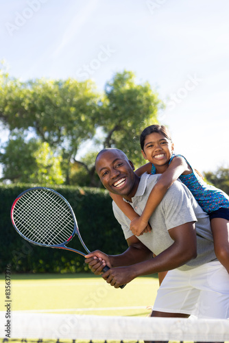 Outdoors, diverse father and daughter enjoying game of tennis together © wavebreak3