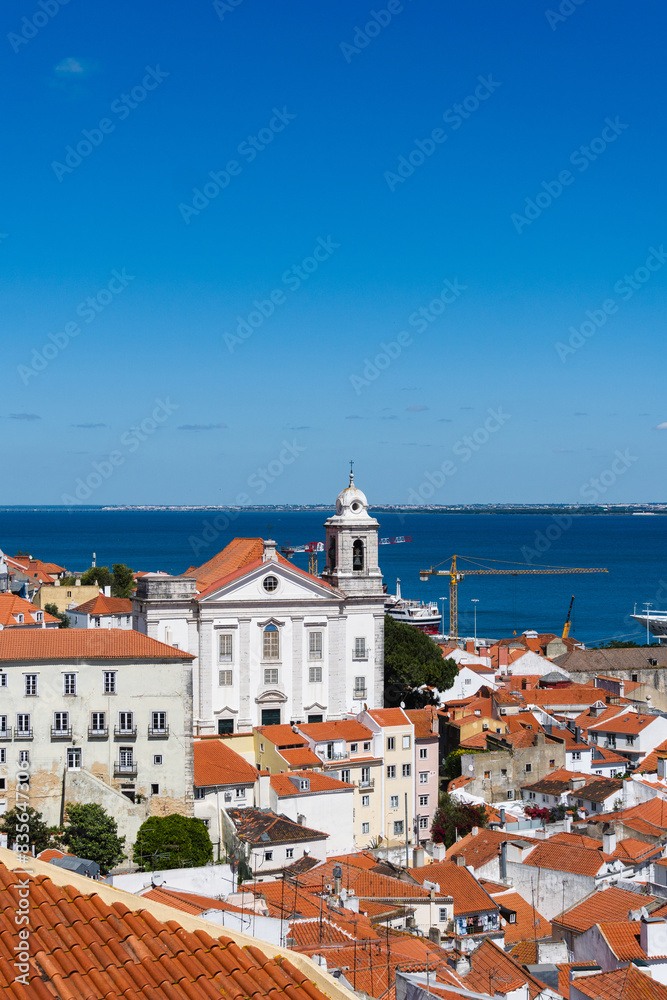 Fototapeta premium View of the beautiful skyline of Lisbon, Portugal, with red roofed, colorful houses in the Alfama district during a sunny day