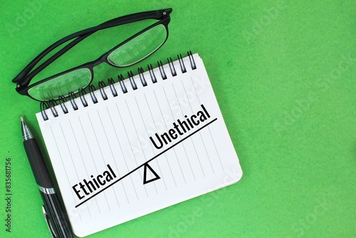 pens, glasses and books with the word ethical or unethical. one's ethical concept photo