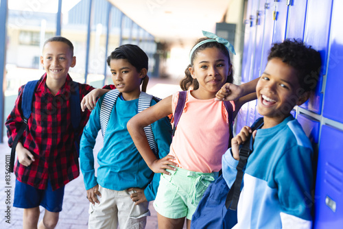 Four biracial children stand confidently by school lockers photo