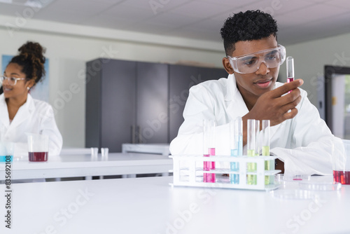 Teenage biracial boy and girl conduct an experiment in a high school lab photo