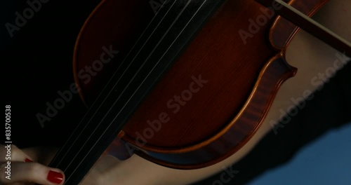 Violinist in black, plays against blue backdrop