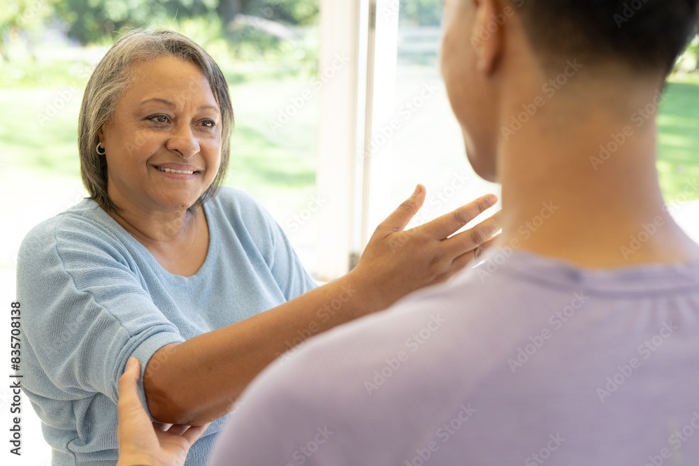 Biracial male physiotherapist with senior female patient in sunlit bright room at home Biracial male physiotherapist with senior female patient in sunlit bright room at home