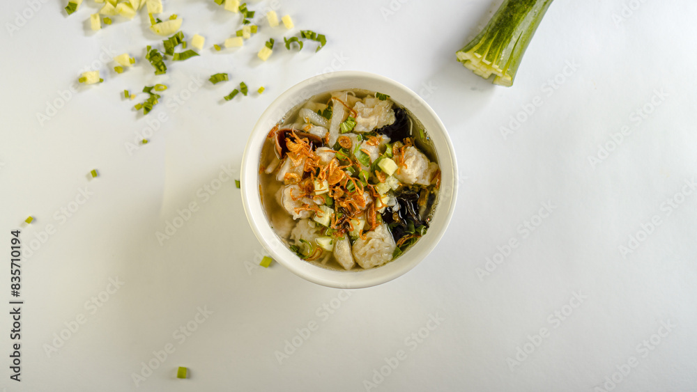 A bowl of tekwan soup garnished with cucumber slices and spring onions A bowl of tekwan soup garnished with cucumber slices and spring onions