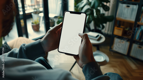 person using smartphone in the living room with white blank screen display mockup