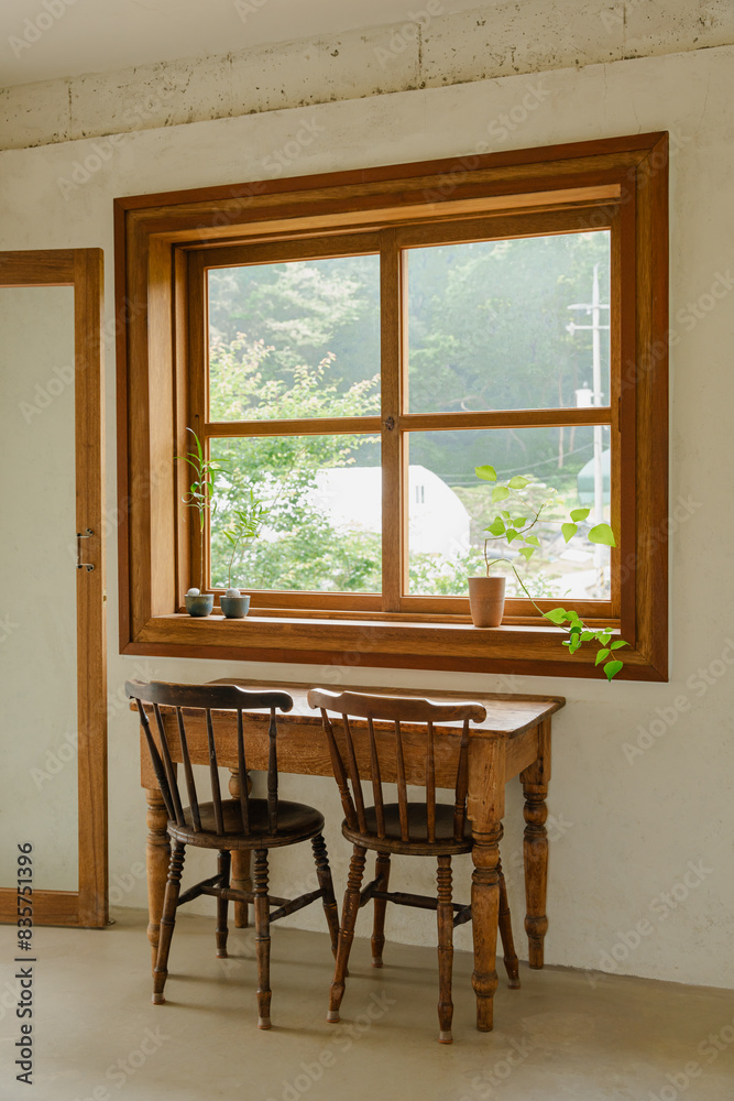 Fototapeta premium Rustic wooden table and chairs by large window