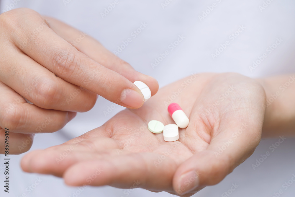 close up hand man taking multiple pills take a medicine in hand holding a cup glass of drinking water on wooden table. Stop drug use Taking Medication health care medical concept.. close up hand man taking multiple pills take a medicine in hand holding a cup glass of drinking water on wooden table. Stop drug use Taking Medication health care medical concept..