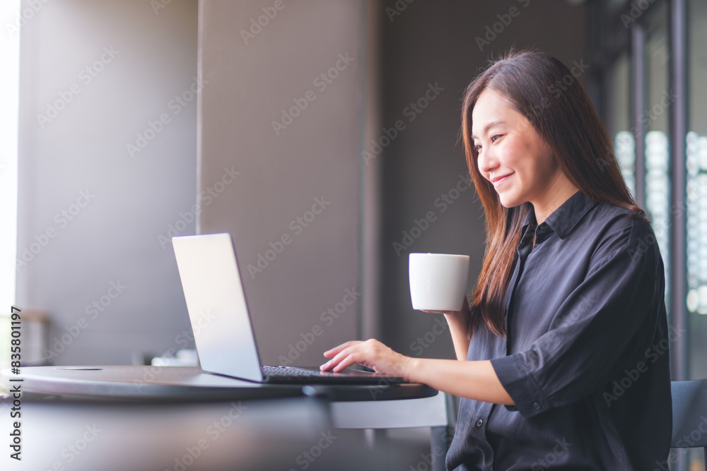 Portrait image of a young woman drinking coffee while working on laptop computer in cafe Portrait image of a young woman drinking coffee while working on laptop computer in cafe