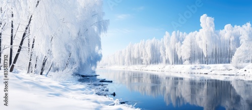 In winter, the flowing river remains unfrozen, reflecting snow-covered trees with massive snowdrifts along its banks, creating a serene copy space image. photo