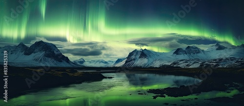 Vibrant green Northern Lights dance over an Icelandic mountain in nature's celestial display, creating a mesmerizing copy space image. © Ilgun