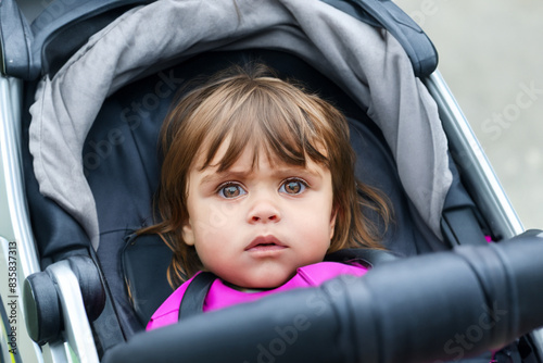 child in a stroller. little girl with short hair sitting in a black baby stroller, top view close up children concept