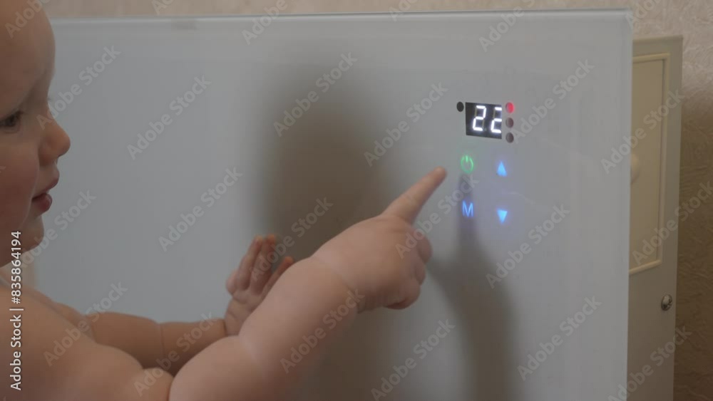 A little boy turns a portable heater on and off. Close-up. The baby indulges and plays with the heating device. Child safety concept. High quality 4k footage