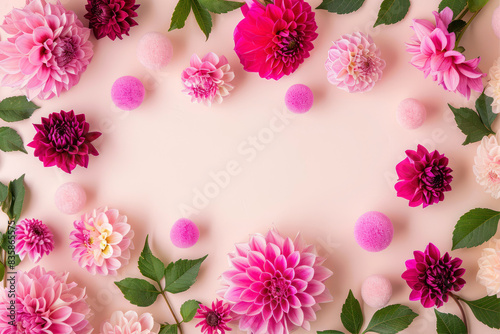 Pink and fuchsia colored flowers  pink paper balls  green leaves  dahlia flower heads  scattered around the frame on a light pastel background in a flat lay.