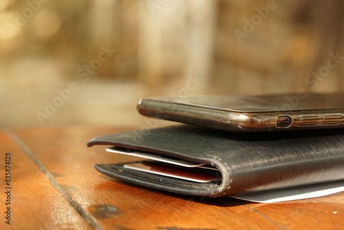Closeup black wallet with cellphone on wood table and blurred background - business cashless 