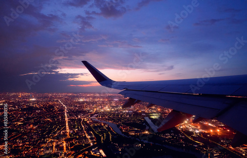 Wing of modern aircraft flying above Paris at night