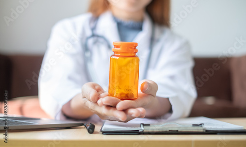 Female doctor holding a medicine bottle is checking the quality of medicine for any side effects the patient or not and recording patient information at the hospital. medical and health care concept
