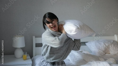 Portrait of happy young woman sitting in bed holding pillow. Video. Happy woman. Life