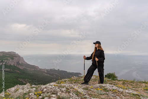 A woman stands on a rocky hill overlooking the ocean
