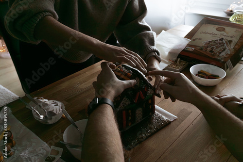 Hands of man and woman. Design of gingerbread cookies house