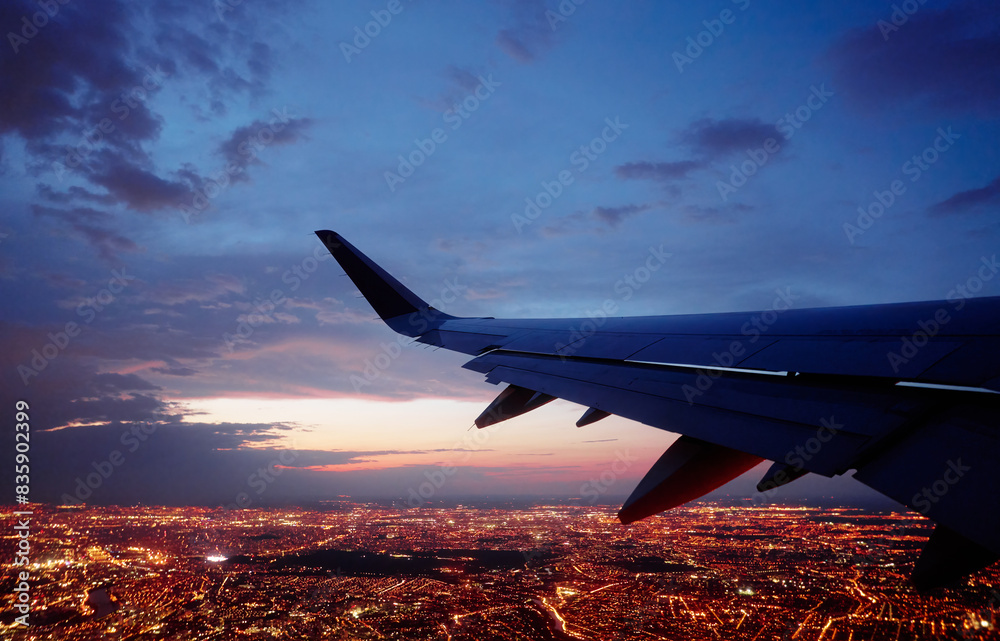 Fototapeta premium Wing of modern aircraft flying above Paris at night