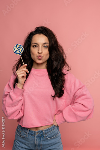 Beautiful dark-haired young lady posing with her favorite hard candy during the studio photo shoot. Love of sweet food concept