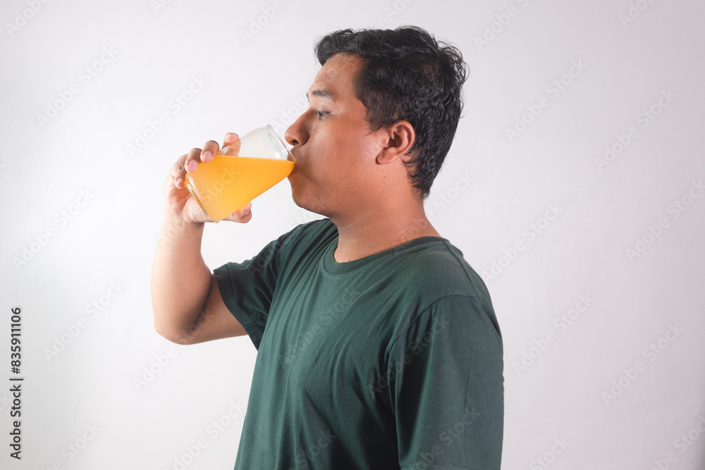 Asian adult man drinking a glass of orange juice isolated on white background Asian adult man drinking a glass of orange juice isolated on white background