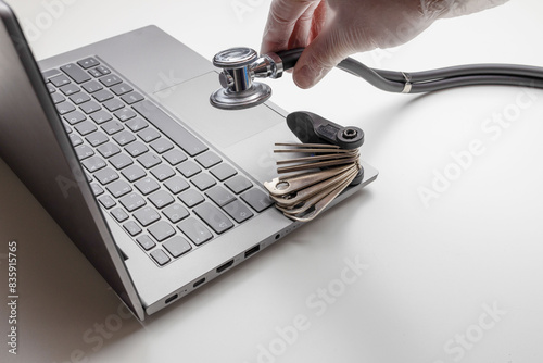 Hand with tool and stethoscope on laptop, closeup. Concept of technical support