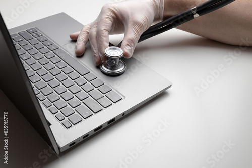 Hand with stethoscope on laptop, closeup. Concept of technical support