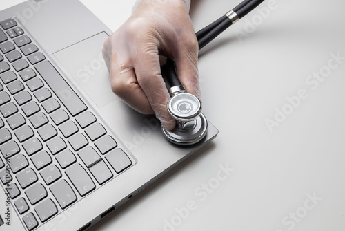 Hand with stethoscope on laptop, closeup. Concept of technical support