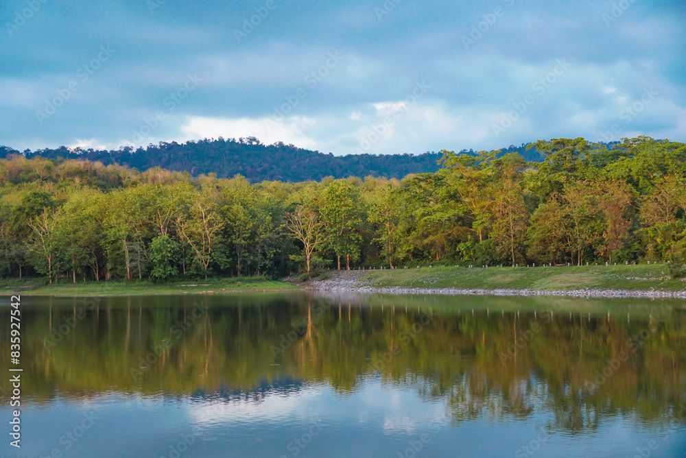 Beautiful nature lake and forest, Nature Study Centre lake and forest at Jedkod Pongkonsao, Saraburi, Thailand. Beautiful view of a golden sun shining over a reflective lake under a cloudy sky Beautiful nature lake and forest, Nature Study Centre lake and forest at Jedkod Pongkonsao, Saraburi, Thailand. Beautiful view of a golden sun shining over a reflective lake under a cloudy sky