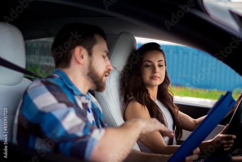 Young woman driving a car with an instructor. Man controlling and checking while holding form. Driving test, driver courses, exam concept © Nataliya