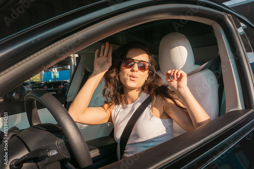 Smiling young woman in sunglasses driving vehicle on the road on a bright day while listening the music. Travel adventure drive, happy summer vacation concept © Nataliya