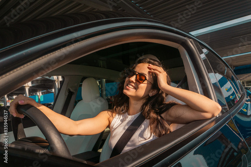 Happy and excited woman sitting in the car on a day trip in the summer, wearing sunglasses. Travel adventure drive, happy summer vacation concept © Nataliya