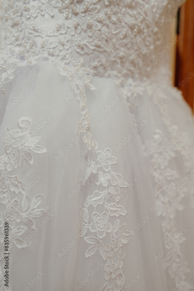 a wedding dress hanging on a hanger in front of a wooden wall a wedding dress hanging on a hanger in front of a wooden wall
