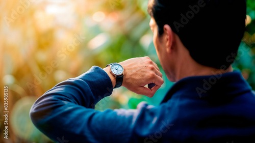 A man in a blue sweater looking at his watch