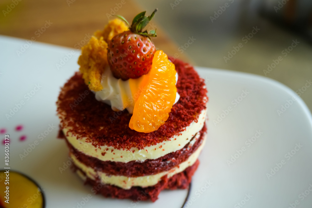 Red velvet cake, classic three layered cake from red butter sponge cakes with cream cheese frosting, with mandarin orange and candied strawberry as topping American cuisine Red velvet cake, classic three layered cake from red butter sponge cakes with cream cheese frosting, with mandarin orange and candied strawberry as topping American cuisine
