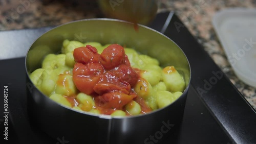 preparing plate of gnocchi with tomato to be served on a plate 